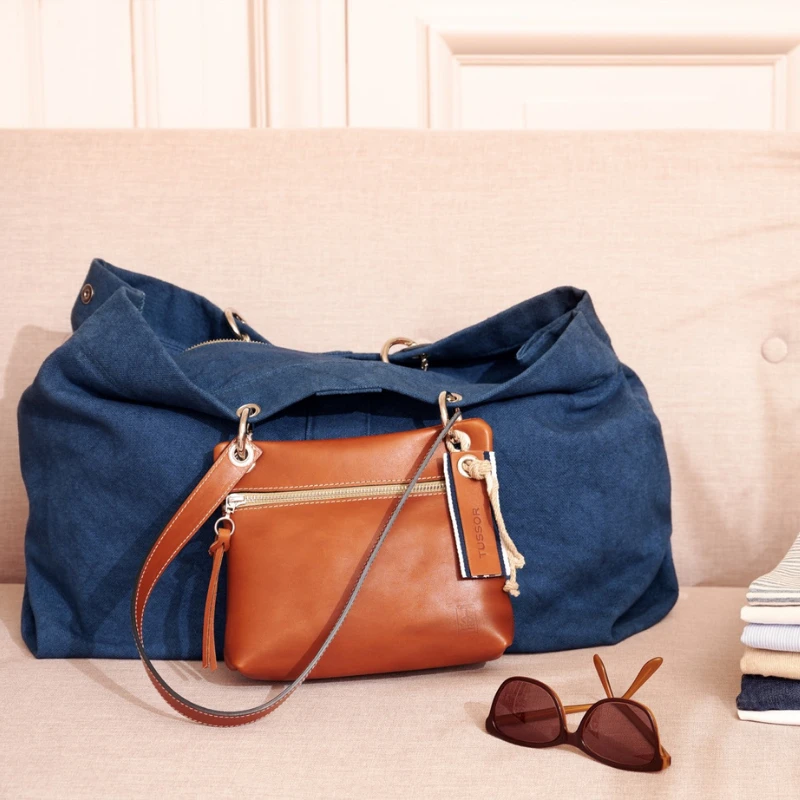 sac modulable en coton bleu canard, pour le week-end, avec des anses en cuir naturel posé sur un canapé