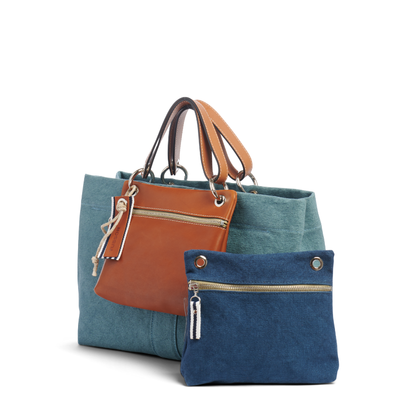 sac de ville modulable en coton bleu français avec des anses en cuir naturel avec des dossiers et sa pochette yole bleu français sur un canapé